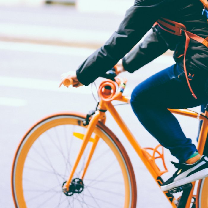 Mann auf orangenem Rennrad in der Stadt